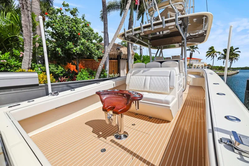 Slide: The Image of 2013 Bahama 41 boat with sleek deck, luxurious seating, and tropical waterfront backdrop. - 24