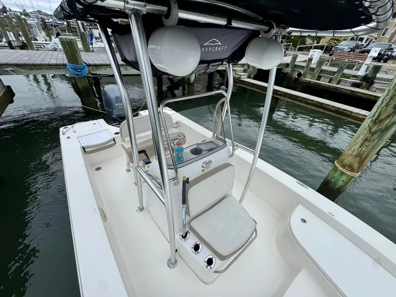 Slide: The Image of A 2015 Robalo 206 Cayman with a T-top, docked, surrounded by water and other boats. - 11
