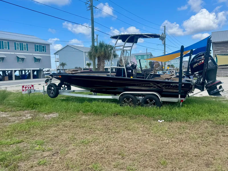 Slide: The Image of A black 2026 Xpress H22 boat on a trailer with a 'For Sale' sign nearby. - 1