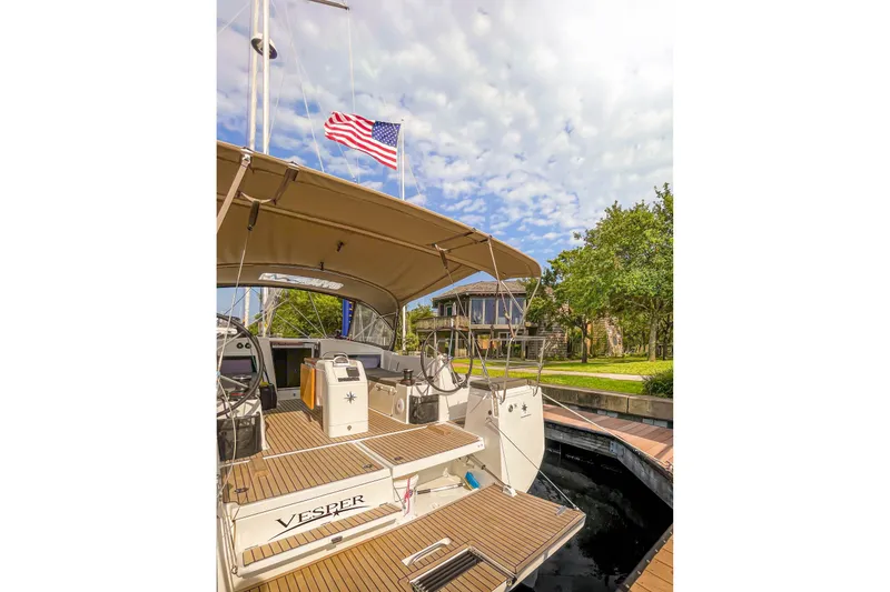 Slide: The Image of 2023 Jeanneau Sun Odyssey 440 yacht docked, featuring a spacious deck and American flag. - 9