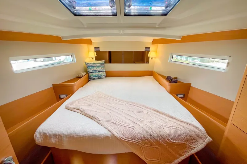 Slide: The Image of Luxurious cabin interior of 2023 Jeanneau Sun Odyssey 440 yacht, featuring cozy bedding and natural light. - 17