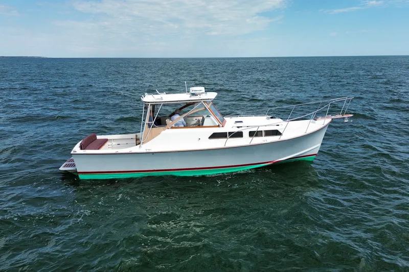 The Image of 1999 Fortier Express 33 boat cruising on open water under a clear sky. - 1