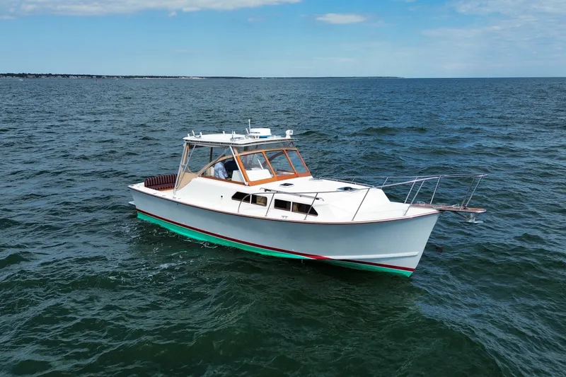 Slide: The Image of 1999 Fortier Express 33 boat cruising on open water under a clear sky. - 2