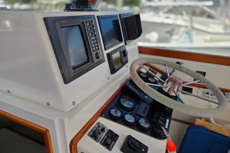 Slide: The Image of Control panel of a 1999 Fortier Express 33 boat with steering wheel and navigation instruments. - 12