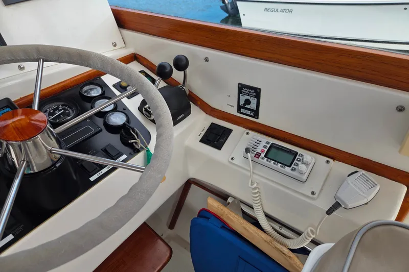 Slide: The Image of Steering wheel and controls of a 1999 Fortier Express 33 boat cockpit. - 14