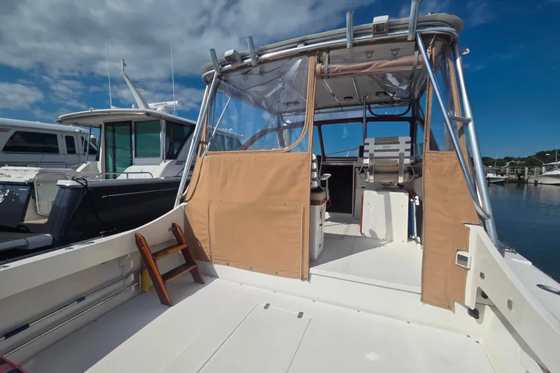 Slide: The Image of 1999 Fortier Express 33 boat docked, featuring a covered cockpit and seating area. - 11