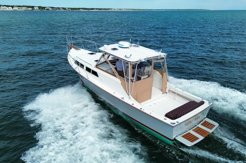 Slide: The Image of 1999 Fortier Express 33 cruising on open water, showcasing sleek design and spacious deck. - 6