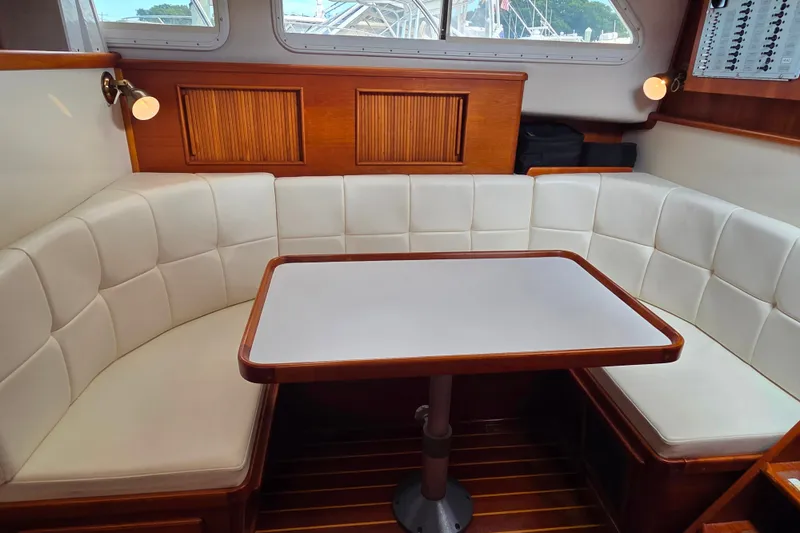 Slide: The Image of Cozy dining area in a 1999 Fortier Express 33 boat with white cushioned seating. - 28