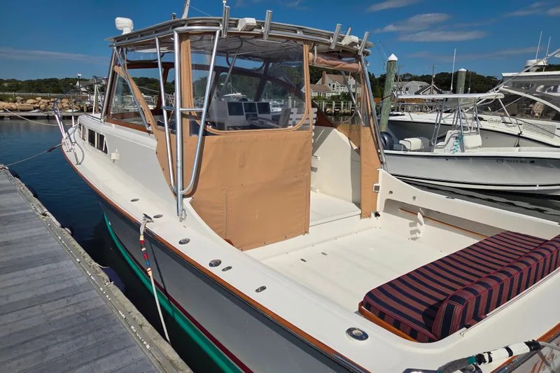 Slide: The Image of 1999 Fortier Express 33 boat docked, featuring a spacious deck and striped seating. - 10