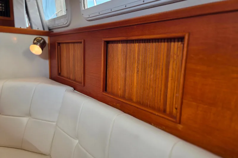 Slide: The Image of Interior of 1999 Fortier Express 33 with wood paneling and white cushioned seating. - 23