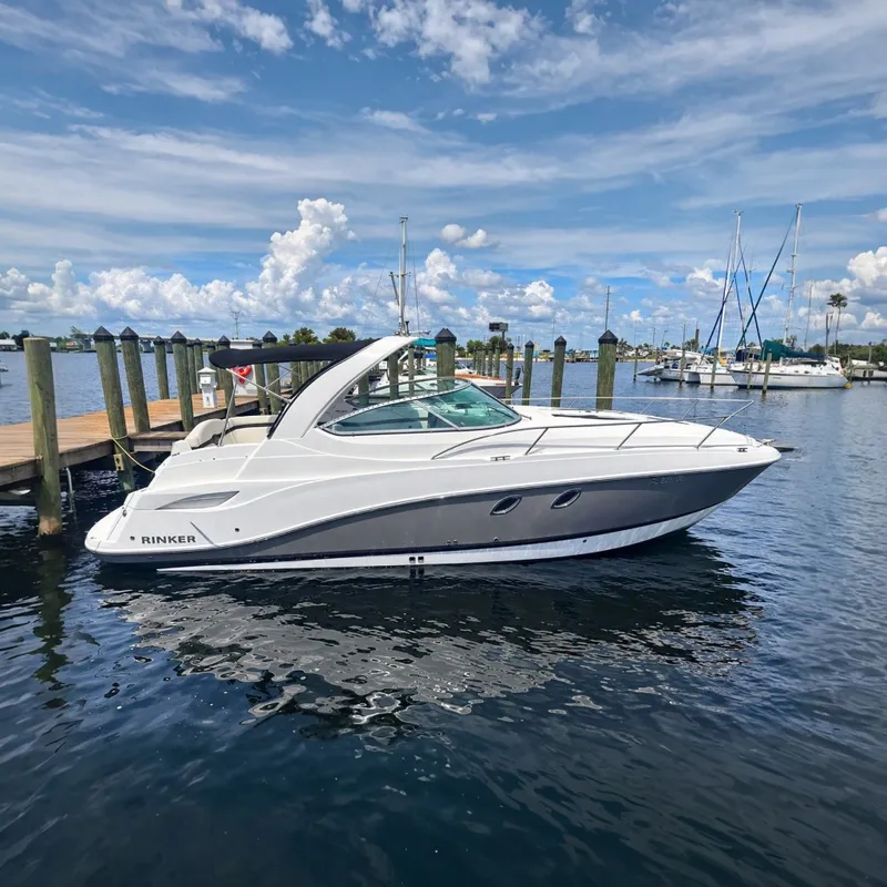 Slide: The Image of A white 2013 Rinker 310 Express Cruiser is docked on a sunny day. - 0