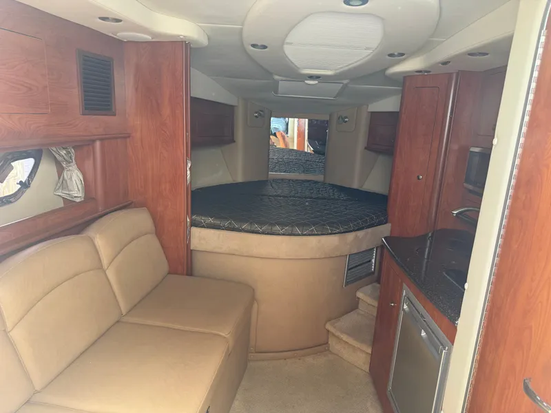 Slide: The Image of Interieur van de Rinker 310 Express Cruiser 2013 met beige bank, houten kasten en ronde slaapruimte. - 7