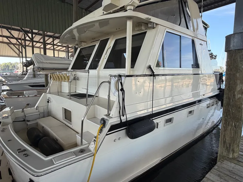 Slide: The Image of A 1991 Hatteras 52 Cockpit Motor Yacht docked in a covered marina. It features a spacious cockpit and large windows. - 6
