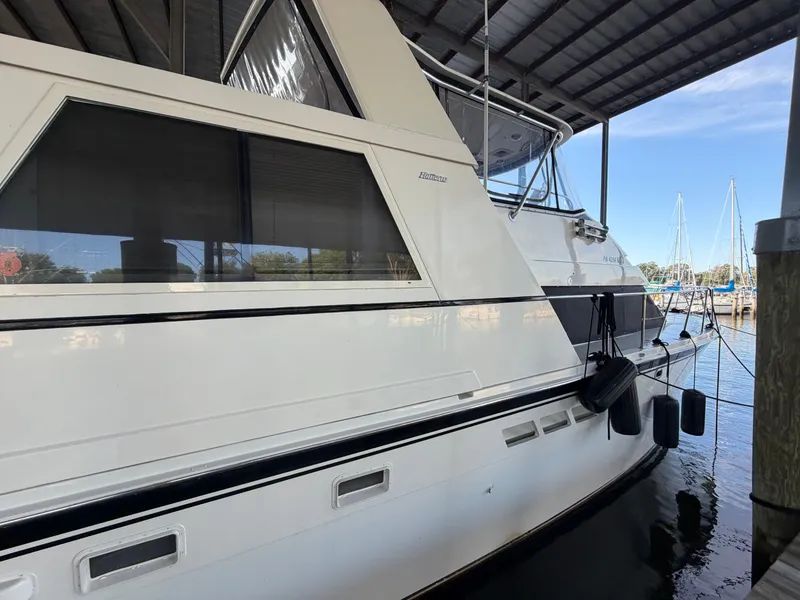 Slide: The Image of A 1991 Hatteras 52 Cockpit Motor Yacht docked in a covered marina. It features a sleek, white design. - 7
