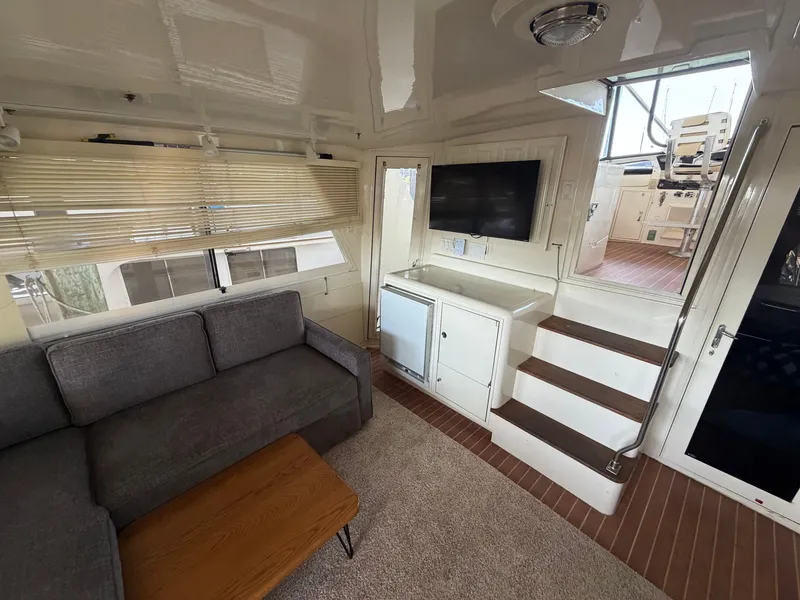 Slide: The Image of Interior of a 1991 Hatteras 52 Cockpit Motor Yacht with gray sofa, TV, and stairs. - 13