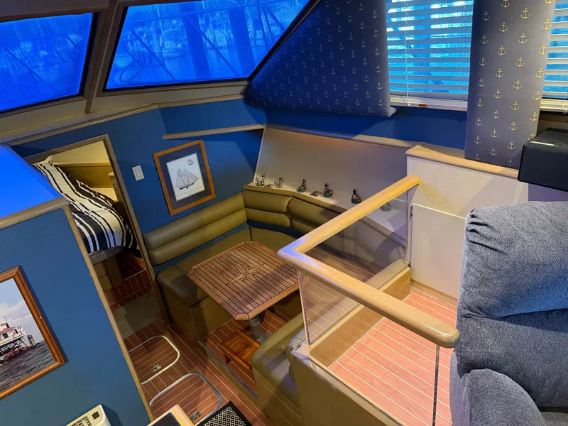 Slide: The Image of The interior of a 1991 Hatteras 52 Cockpit Motor Yacht features a cozy seating area with a wooden table and nautical decor. - 37