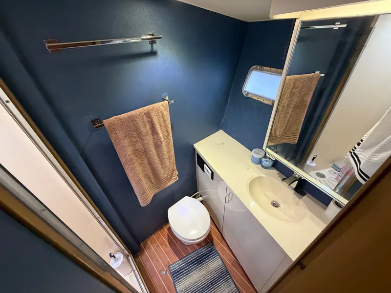 Slide: The Image of The image shows a yacht bathroom with blue walls, a sink, and a toilet. - 46