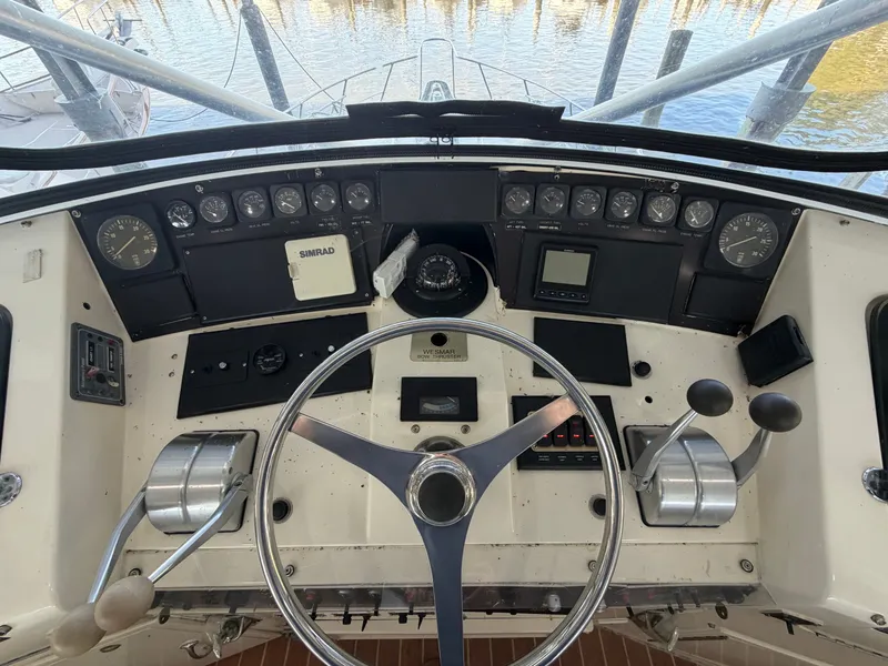 Slide: The Image of The image shows the helm of a 1991 Hatteras 52 Cockpit Motor Yacht with various instruments and controls. - 27