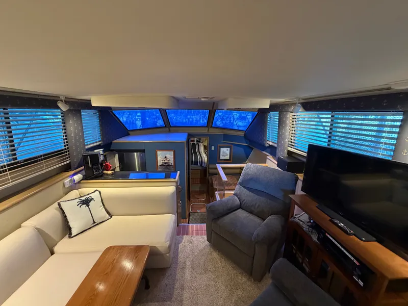 Slide: The Image of The interior of a 1991 Hatteras 52 Cockpit Motor Yacht features a cozy living area with sofas and a TV. - 31