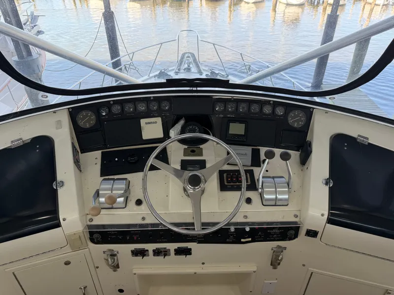 Slide: The Image of The image shows the helm of a 1991 Hatteras 52 Cockpit Motor Yacht with a sleek steering wheel and instruments. - 23