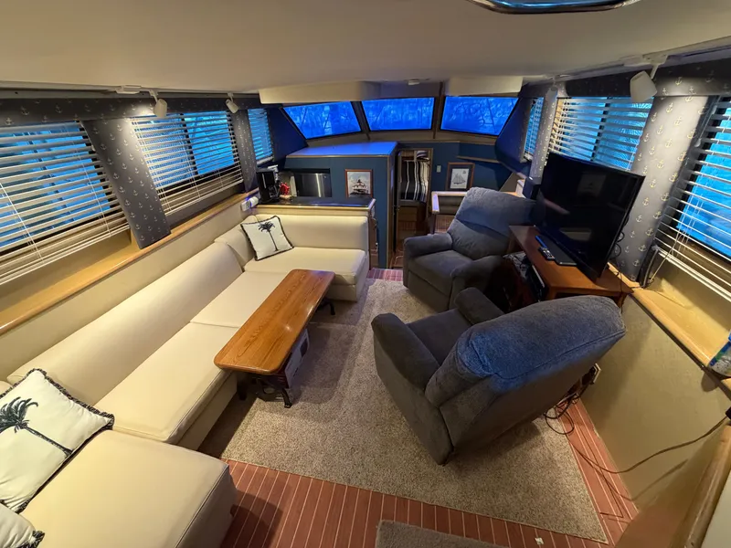 Slide: The Image of The interior of a 1991 Hatteras 52 Cockpit Motor Yacht features a cozy living area with sofas, armchairs, and a TV. - 29
