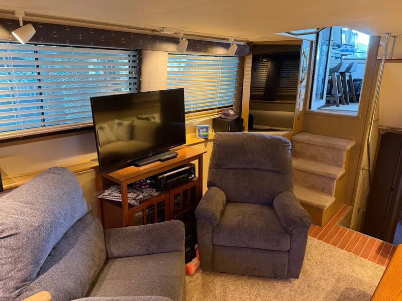Slide: The Image of The interior of a 1991 Hatteras 52 Cockpit Motor Yacht features cozy seating, a TV, and stairs. - 34