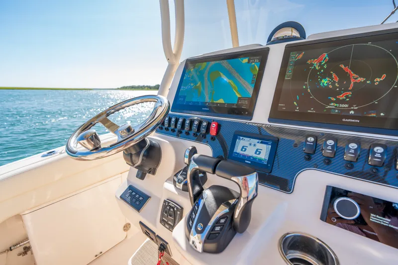 Slide: The Image of 2023 Grady-White Canyon 271 FS boat dashboard with navigation screens and controls. - 14