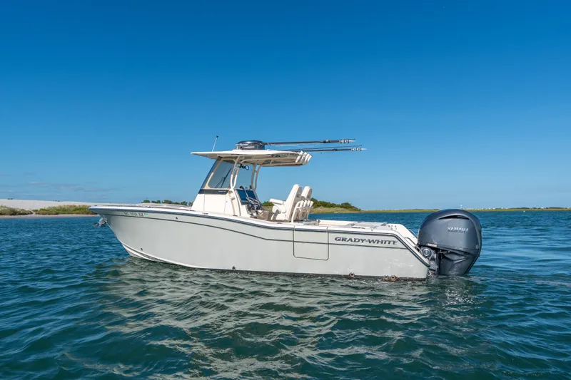 Slide: The Image of 2023 Grady-White Canyon 271 FS boat on calm water under clear blue sky. - 2
