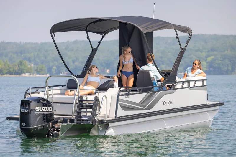 Slide: The Image of 2026 Tahoe Pontoon Sport 85 Versatile Rear Bench on a serene lake with passengers enjoying the sun. - 8
