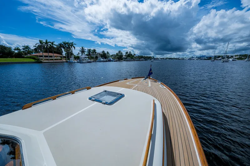 Slide: The Image of Hinckley Picnic Boat 37 MKIII cruising on a scenic waterway under a partly cloudy sky. - 6