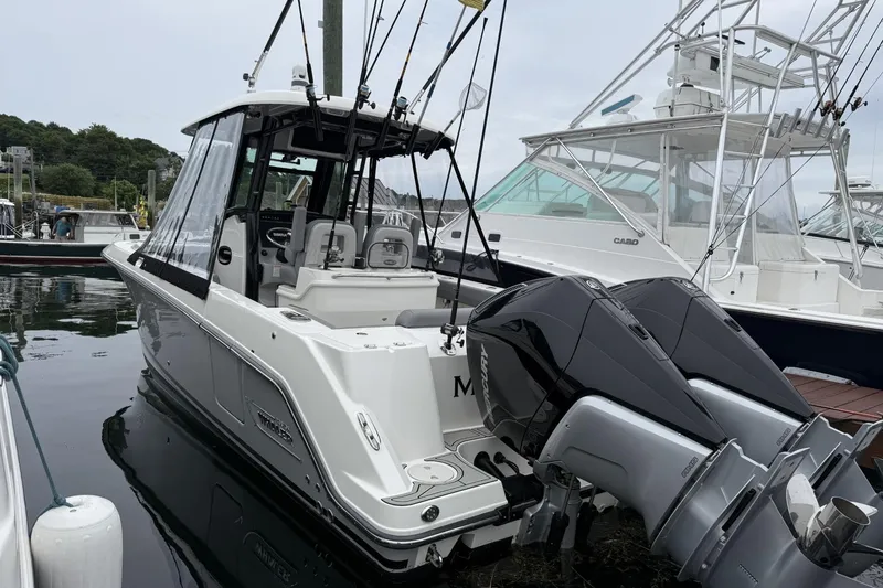 The Image of 2024 Boston Whaler 280 Outrage boat docked, featuring dual outboard engines and sleek design. - 1