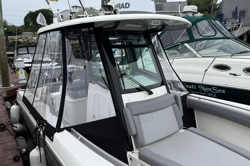 Slide: The Image of 2024 Boston Whaler 280 Outrage boat docked, featuring sleek design and protective canopy. - 8