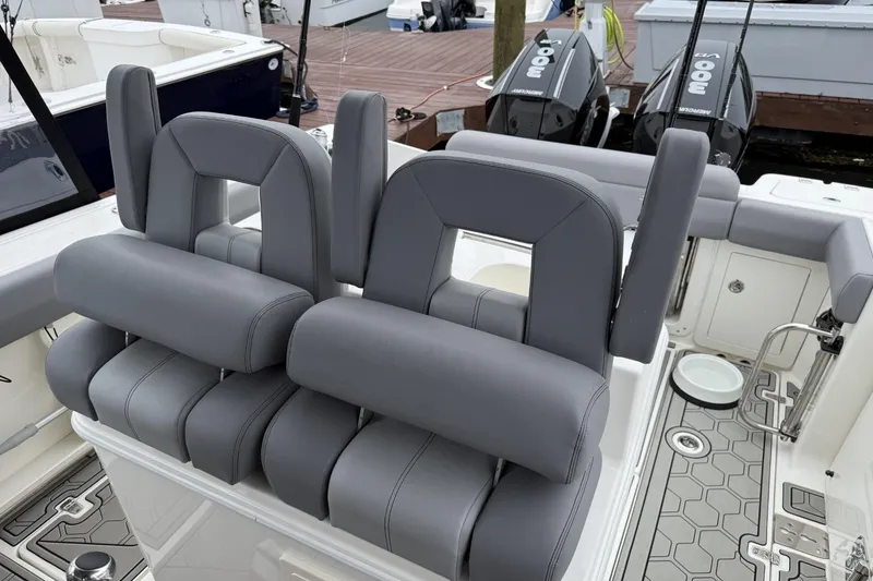 Slide: The Image of 2024 Boston Whaler 280 Outrage boat interior with gray seating and dual outboard engines. - 14