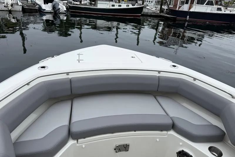 Slide: The Image of 2024 Boston Whaler 280 Outrage boat interior with cushioned seating at dock. - 19