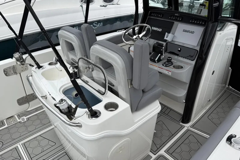 Slide: The Image of 2024 Boston Whaler 280 Outrage interior with fishing rods and modern helm controls. - 6
