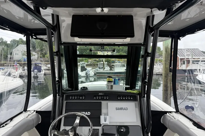 Slide: The Image of 2024 Boston Whaler 280 Outrage helm with Simrad electronics, docked at a marina. - 12