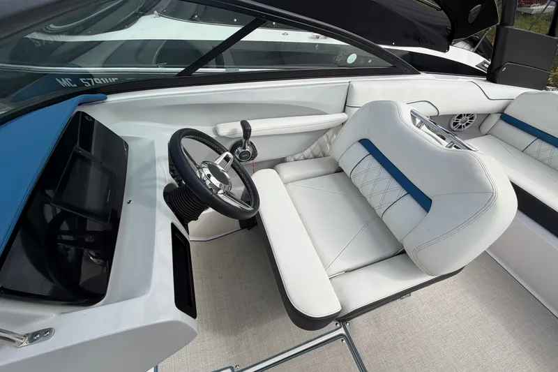 Slide: The Image of 2021 Regal LS2 Surf boat interior with white and blue seating, steering wheel, and dashboard. - 9