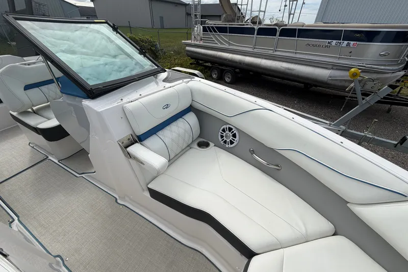 Slide: The Image of 2021 Regal LS2 Surf boat interior with white and blue seating, docked near another boat. - 12