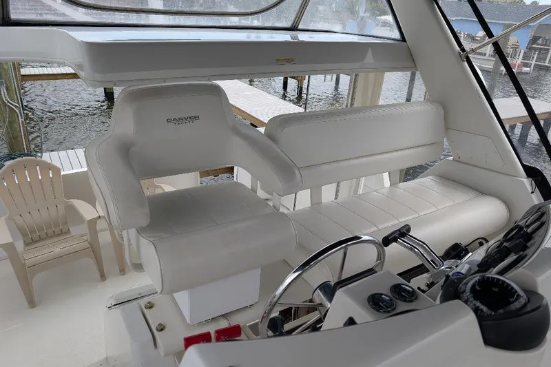 Slide: The Image of 2003 Carver 356 Motor Yacht helm with white seating and steering wheel. - 17