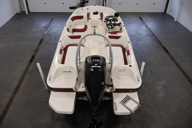 Slide: The Image of 2015 Bayliner Element 180 XL boat with red seating, viewed from the rear in a garage. - 10