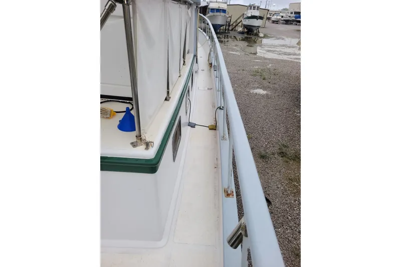 Slide: The Image of 1980 DeFever 41 Trawler deck view with railing and docked boats in background. - 14