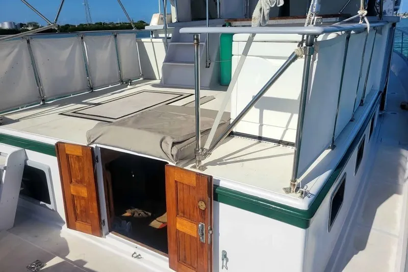 Slide: The Image of 1980 DeFever 41 Trawler deck with wooden doors and railing, under clear blue sky. - 2