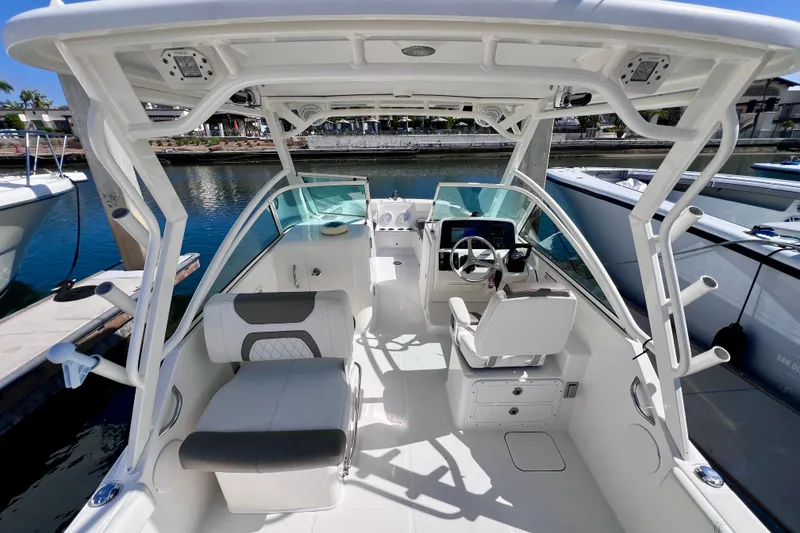 Slide: The Image of 2021 World Cat 230 DC boat interior with seating and steering wheel at dock. - 9