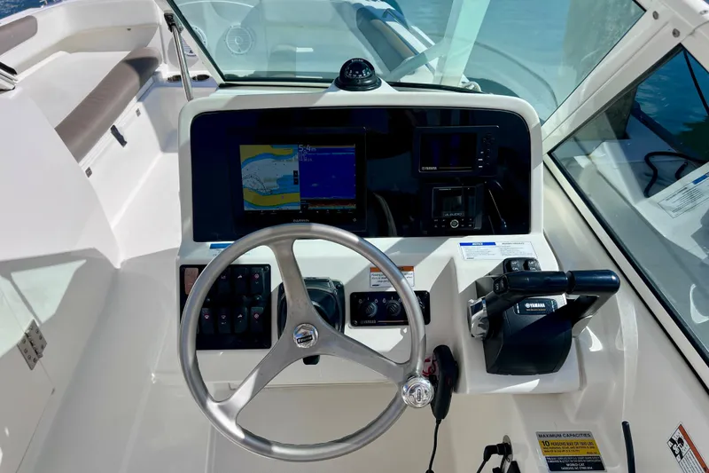 Slide: The Image of Cockpit of 2021 World Cat 230 DC boat with steering wheel and navigation controls. - 14