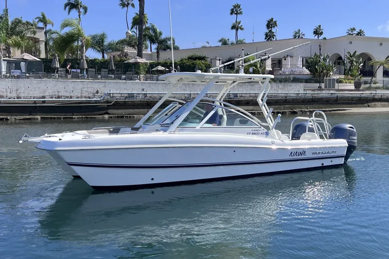 Slide: The Image of 2021 World Cat 230 DC boat on calm water, with palm trees and buildings in the background. - 3