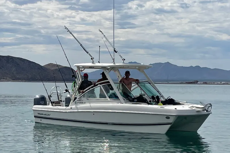 Slide: The Image of 2021 World Cat 230 DC boat on calm water with fishing rods, mountains in background. - 4