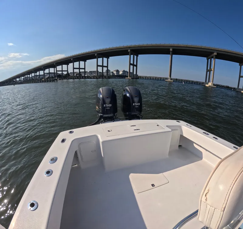 Slide: The Image of A 2018 Foster 26 boat with twin outboard engines on calm water beneath a bridge. - 3