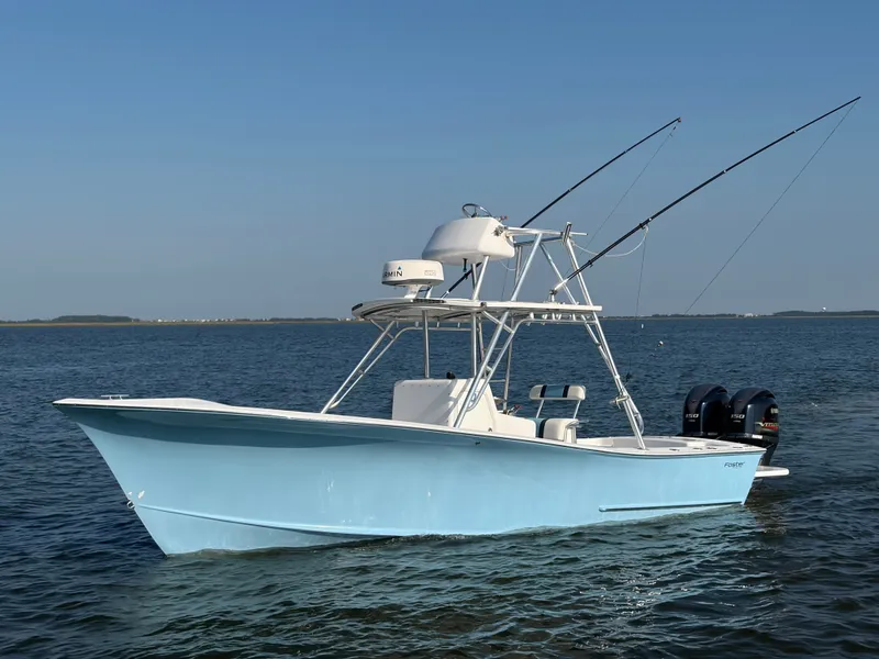 Slide: The Image of A light blue Foster 26 boat floats on calm water. It features two fishing rods. - 1