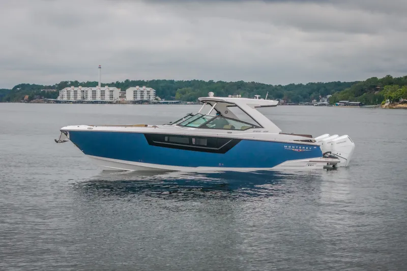 Slide: The Image of 2025 Monterey 385SS Super Sport boat on calm water, with scenic shoreline background. - 67
