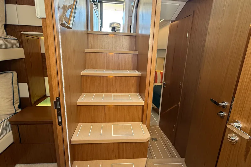 Slide: The Image of Interior view of 2026 Tiara Yachts EX 54, featuring wooden stairs and cozy cabin design. - 26